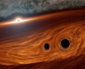 Two black holes are embedded inside a dense disk. A third supermassive black hole is at the center of the disk.