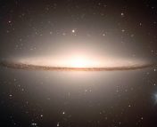 An eliptical galaxy viewed edge on. The galaxy is very bright in the center and is surrounded by a dust looking disk