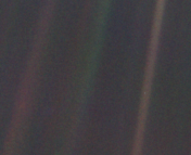 A fuzzy picture that is mostly black, with a strips of red and green vertically through the image. Down the center of one of the red stripes, a tiny green-blue dot can be seen, the size of a pixel