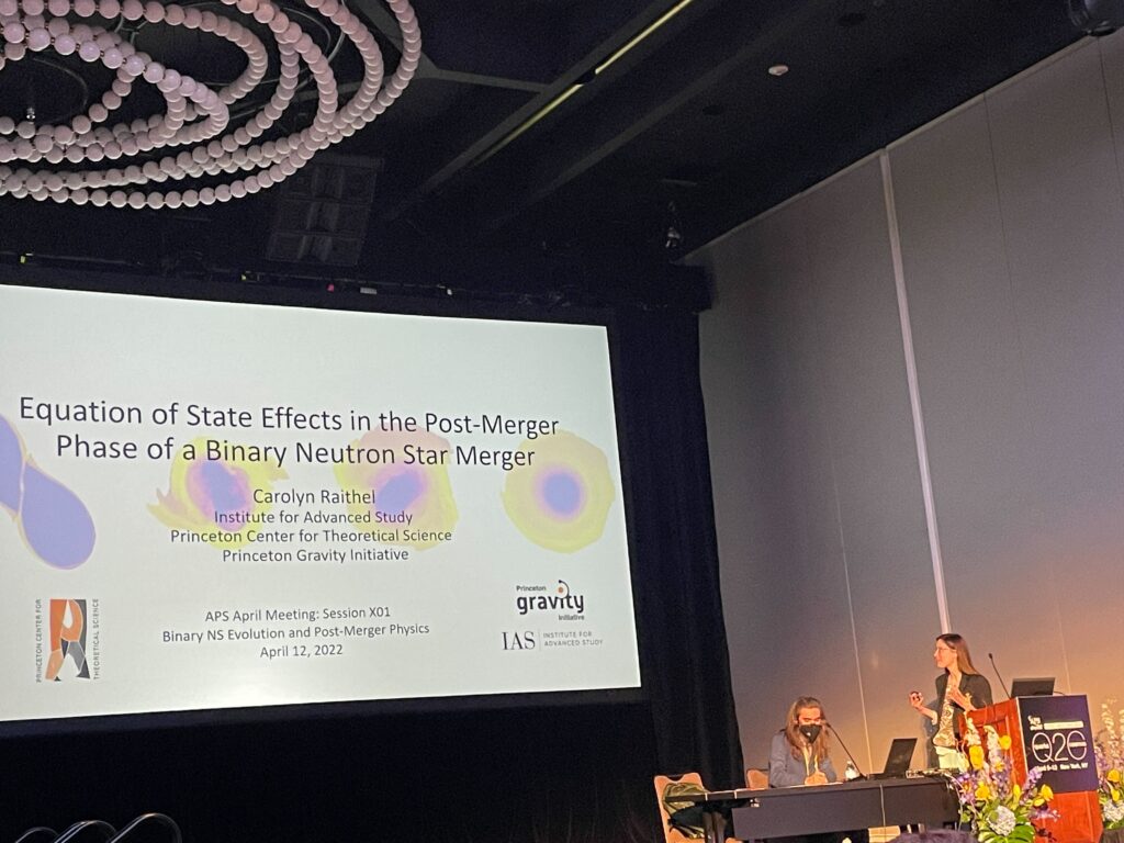 APS April meeting speaker Carolyn Raithel stands and gestures at a slide on a talk covering neutron star mergers. The session chair, Salvatore Vitale is seated next to her.