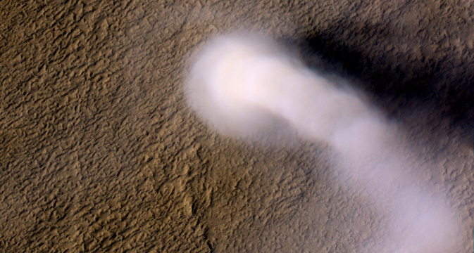 An image of a dust devil on Mars. A white funnel-like cloud can be seen rising from the Martian surface.