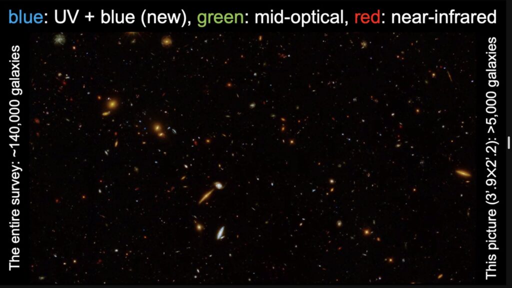 Black background with many specks, some of which are larger and look like galaxies