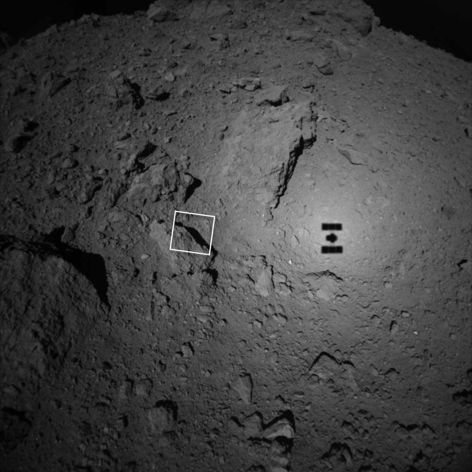 Photo of Ryugu taken slightly above the surface. The shadow of Hayabusa 2 can be seen on the ground. 