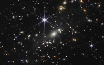 A photograph completely filled with bright galaxies and some stars of all different colors. Some of the galaxies look markedly warped and distorted.