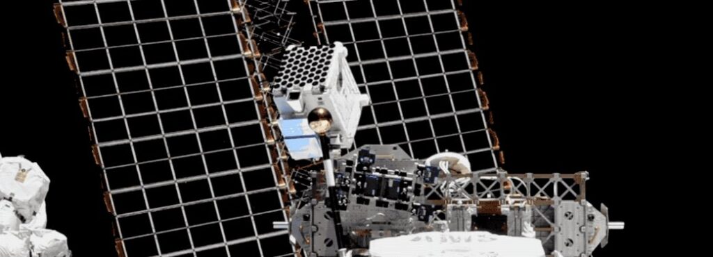 A photograph of NICER mounted on the International Space Station, with two of the ISS's solar panels in the background.