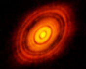 ALMA image of the protoplanetary disk around HL Tau. A bright yellow circle in the center of the image is surrounded by a series of bright orange and red rings at increasing radii around it