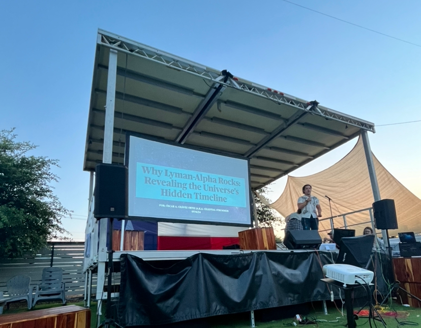 Oscar stands on a stage next to a projection screen. On the screen he presents slides for his presentation, "Why Lyman-Alpha Rocks: Revealing the Universe's Hidden Timeline".