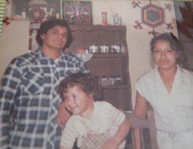 Jorge Moreno as a child climbing on a chair between two adults, his parents