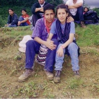 Two people sitting on a grassy hill holding hands