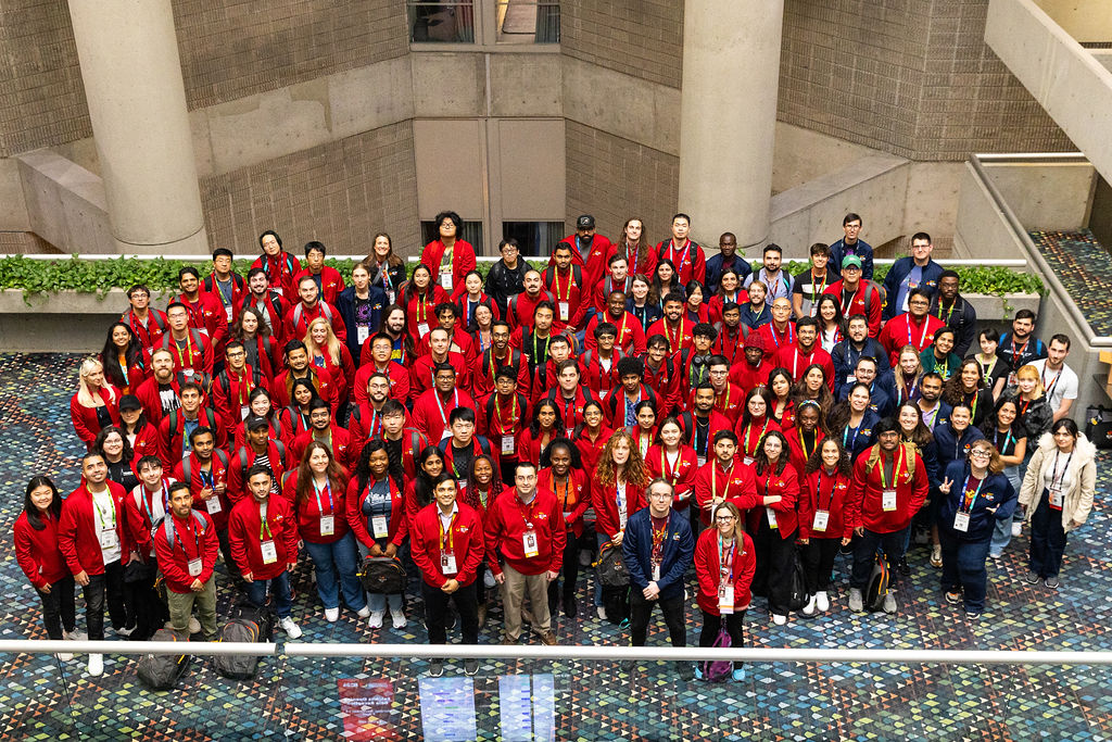 A group of a large number of students wearing matching red volunteer jackets.