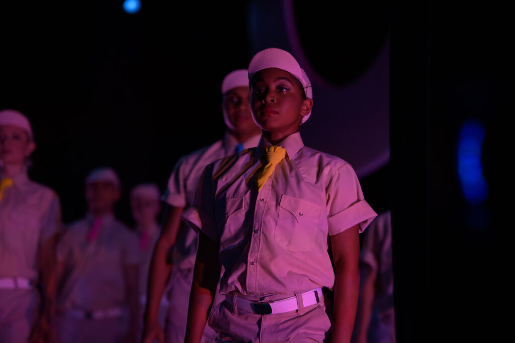 Ballet dancer dressed as a scout in dim purple lighting