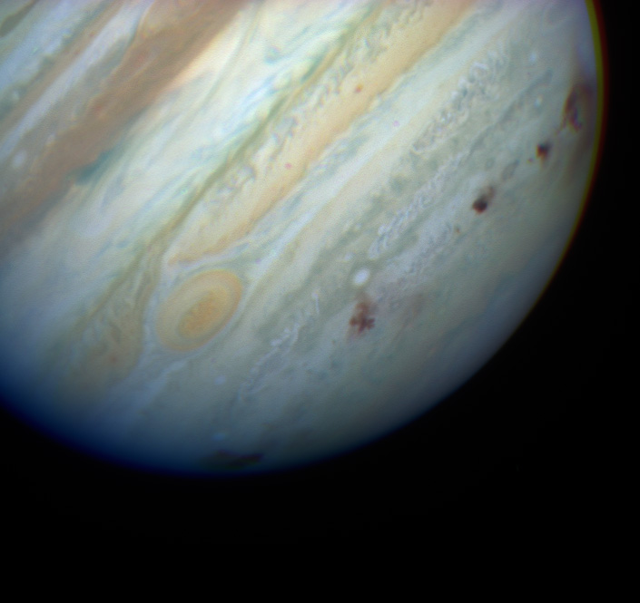 An image of Jupiter with six dark spots where the Shoemaker-Levy comet fragments impacted the planet.