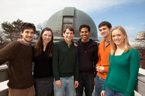 Four men and two women standing on the roof of the Center for Astrophysics in front of a telescope dome.