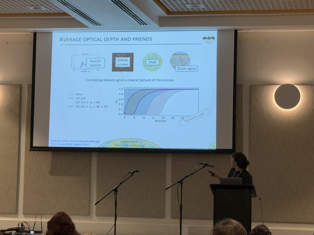 Adélie Gorce stands at a podium presenting a slide titled “Average Optical Depth and Friends.” The slide shows schematic icons for quasar spectra, galaxy surveys, the CMB, and 21 cm signals, along with a plot of ionized fraction versus redshift demonstrating how combining these datasets tightens constraints on the reionization history. The note “Daniela’s talk” appears on the plot, and the slide credits Gorce and collaborators.

