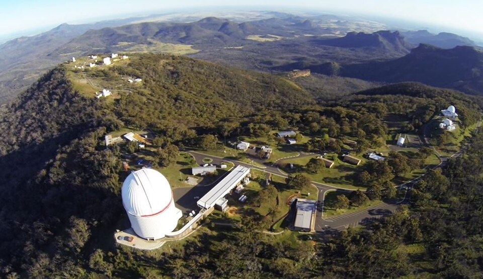 Aerial view of Siding Spring Mountain. Anglo-Australian Telescope dome visible near centre of image, among green mountains.
